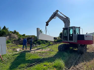 Kettenbagger setzt Betonfertigteil bei Bauarbeiten ein